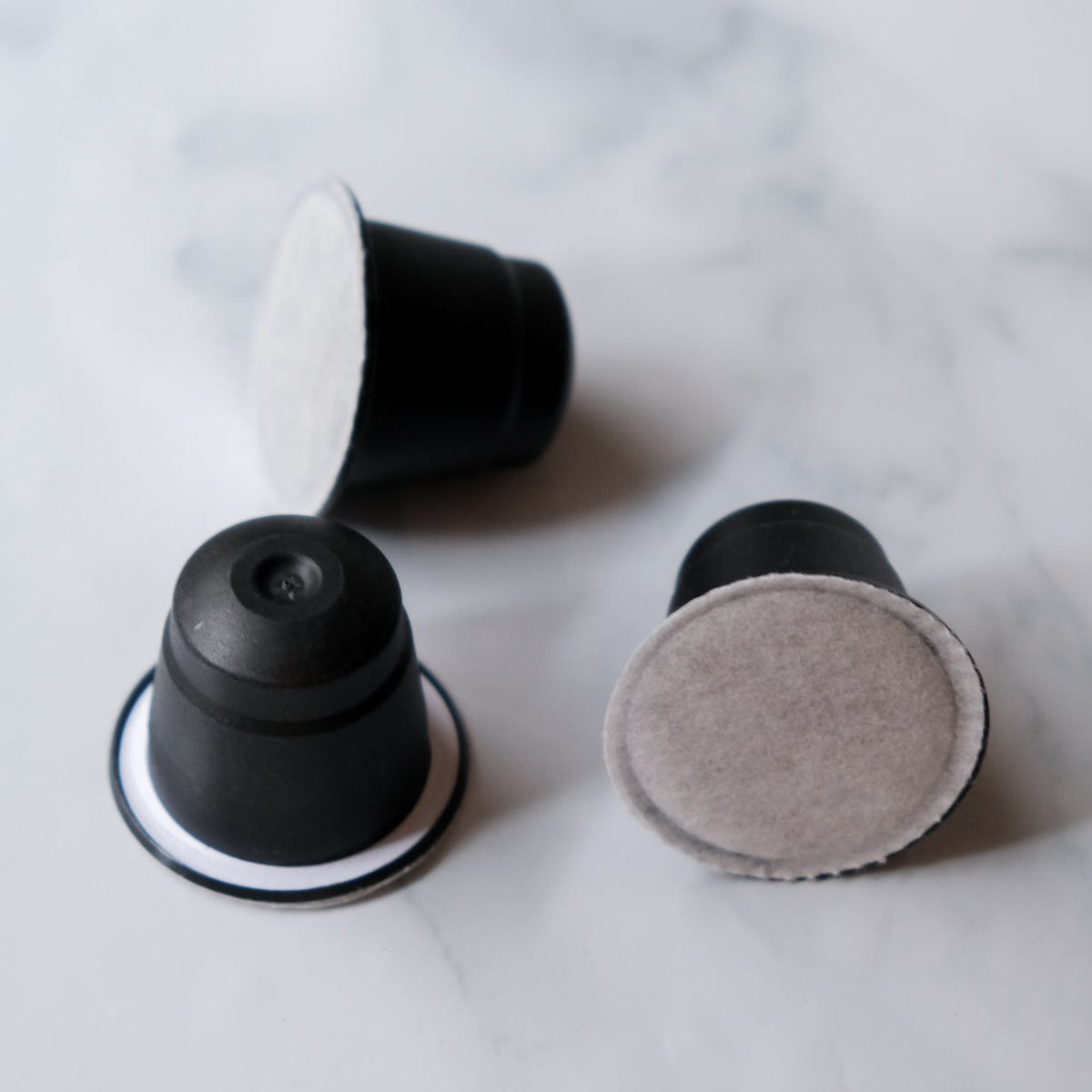 Three coffee nespresso capsules on a marble surface